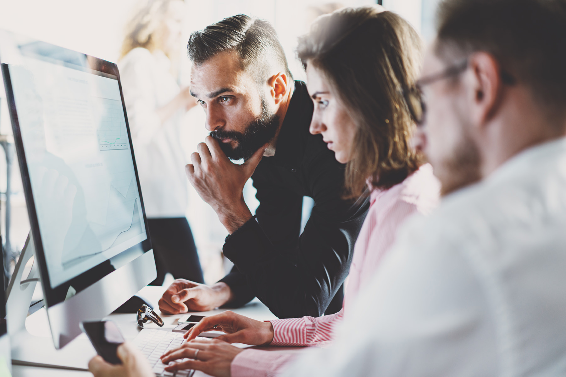 three people reviewing information on a computer
